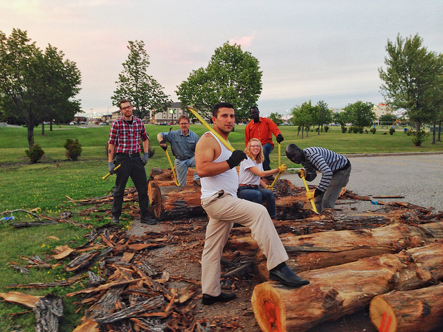 Dwight Mickelson, (2nd left) leads a community of participants in debarking the logs that eventually create the giant log marimba emerging from the Listening Garden, providing a visual rhythm and exciting play for children